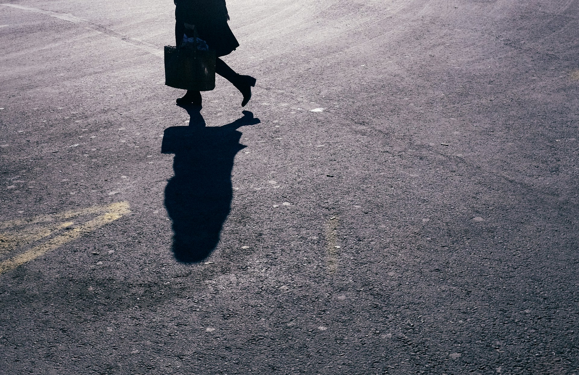 person in black coat and boots walking on street