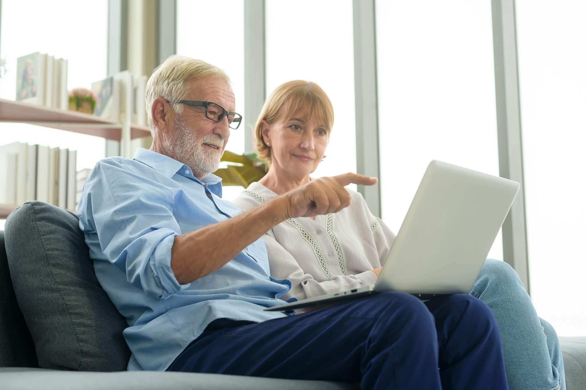 A senior-aged man and woman looking at a laptop together, representing Ontario pension plans and principles-based regulation